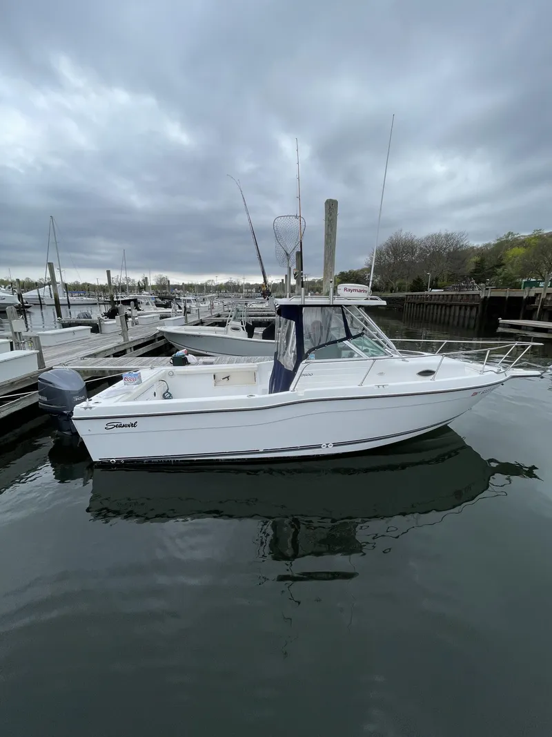 Slide: The Image of 2000 Seaswirl Striper WALKAROUND boat docked in a marina under cloudy skies. - 1