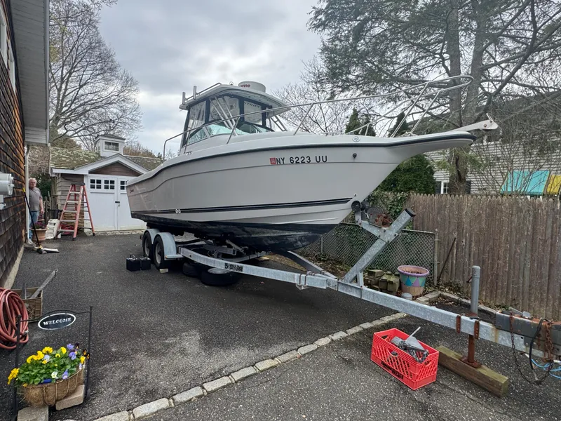 Slide: The Image of 2000 Seaswirl Striper WALKAROUND boat on trailer in driveway, surrounded by trees and house. - 6