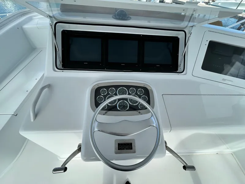Slide: The Image of 2001 Viking 55 Convertible yacht helm with steering wheel and multiple navigation screens. - 25