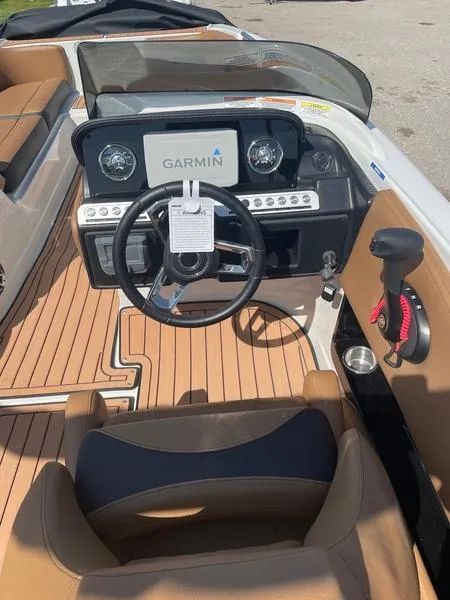 Slide: The Image of 2023 Crownline E225 XS boat cockpit with Garmin display and tan seating. - 5