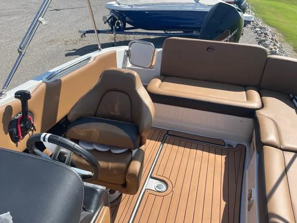 Slide: The Image of 2023 Crownline E225 XS boat interior with tan seating and wood-style flooring. - 9