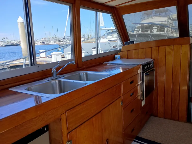 Slide: The Image of 1978 Pacific Bluefin SPF boat interior with wooden cabinetry, dual sink, and marina view. - 16