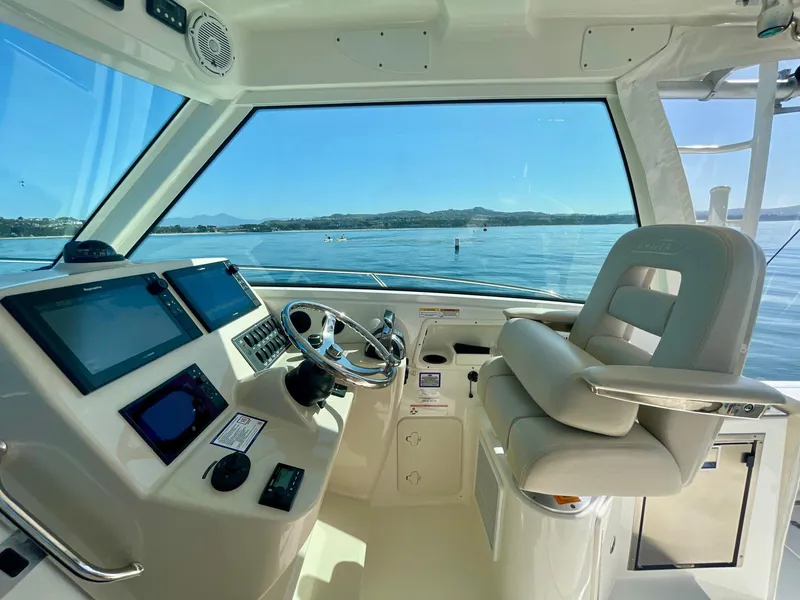 Slide: The Image of 2018 Boston Whaler 315 Conquest helm with modern controls and scenic ocean view. - 11