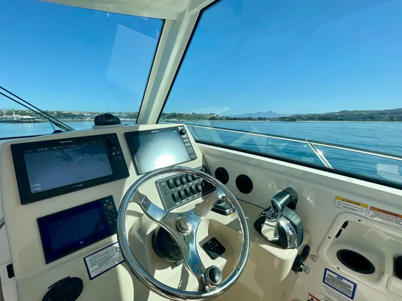 Slide: The Image of Helm of 2018 Boston Whaler 315 Conquest with navigation screens and steering wheel. - 12