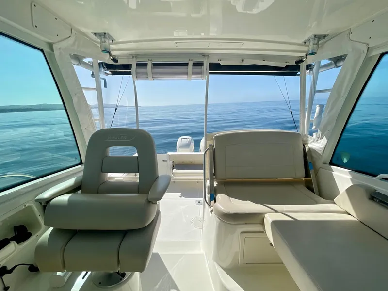 Slide: The Image of 2018 Boston Whaler 315 Conquest interior with seating, ocean view, and fishing rods. - 18