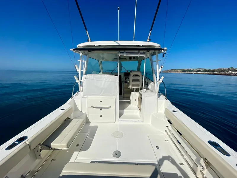 Slide: The Image of 2018 Boston Whaler 315 Conquest boat on calm water, showcasing spacious deck and seating. - 19