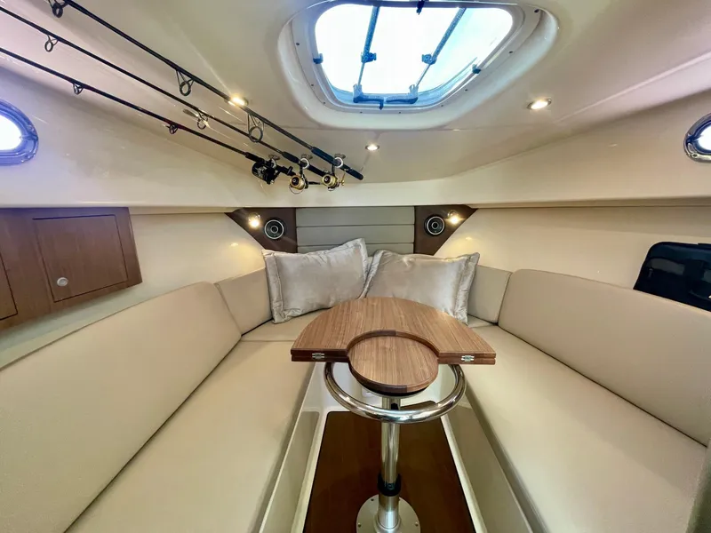 Slide: The Image of 2018 Boston Whaler 315 Conquest cabin interior with seating, table, and fishing rods. - 31