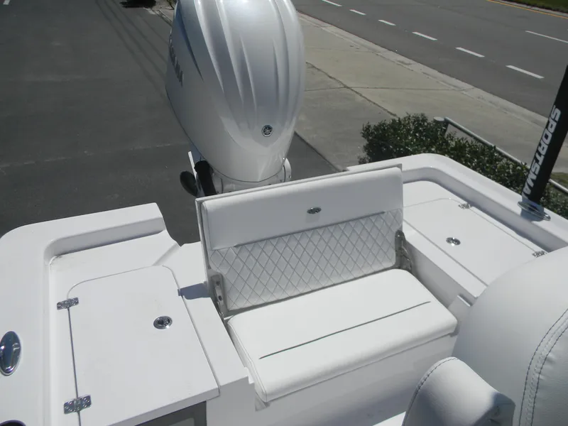 Slide: The Image of 2025 Sportsman Masters 247 Bay Boat with white seating and engine, parked on a road. - 29