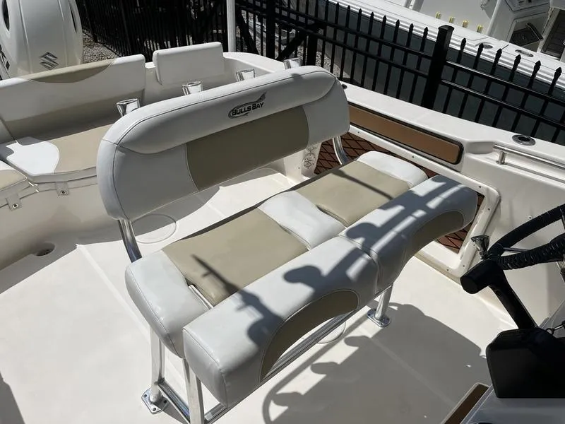 Slide: The Image of 2020 Bulls Bay 230 Center Console boat seating area with cushioned bench and steering wheel. - 15
