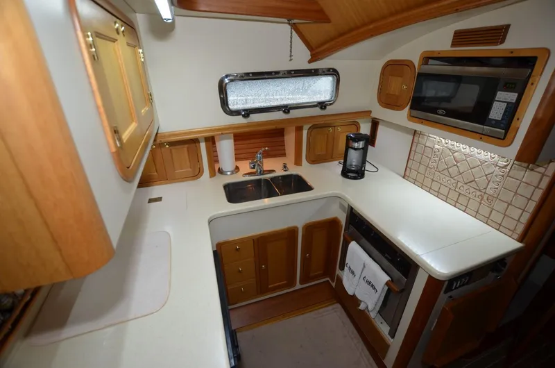 Slide: The Image of 2006 Legacy Yachts Sedan kitchen with wooden cabinetry, sink, and appliances. - 10