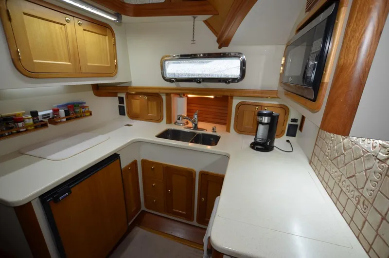 Slide: The Image of 2006 Legacy Yachts Sedan kitchen with wooden cabinets, sink, and appliances. - 11