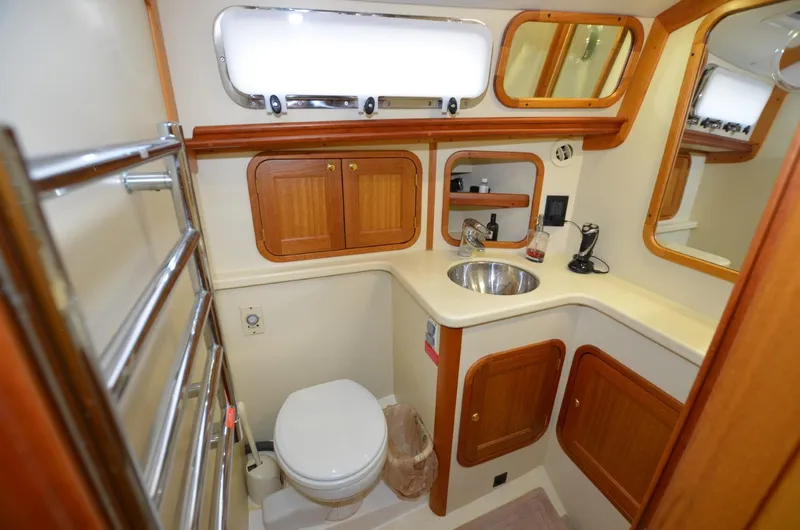 Slide: The Image of 2006 Legacy Yachts Sedan bathroom with wooden cabinets, sink, and toilet. - 14