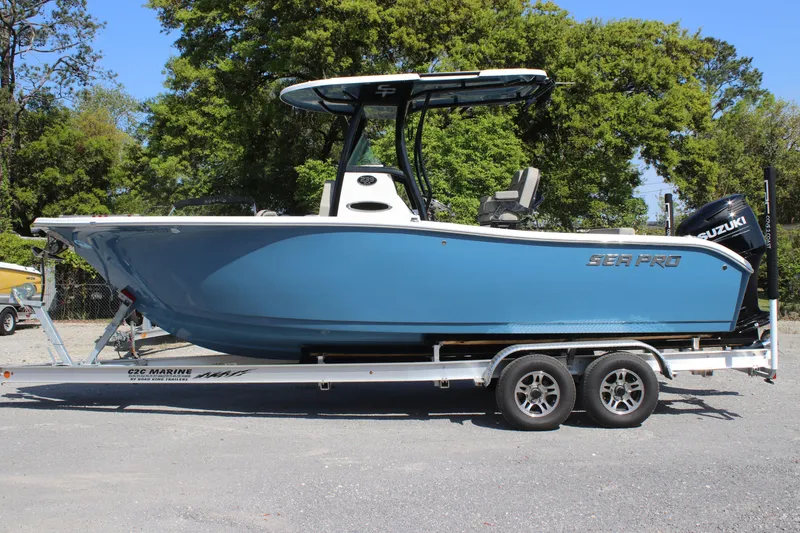 Slide: The Image of 2023 Sea Pro 239 Deep V CC boat on trailer, blue hull, parked outdoors. - 0