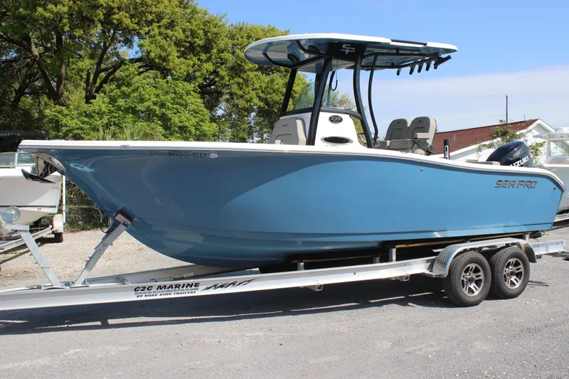 Slide: The Image of 2023 Sea Pro 239 Deep V CC boat on trailer, blue hull, parked outdoors. - 1