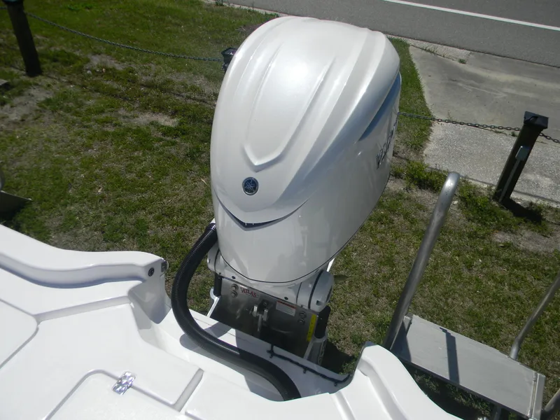 Slide: The Image of 2025 Sportsman Masters 267 Bay Boat engine, white exterior, parked on grass. - 10