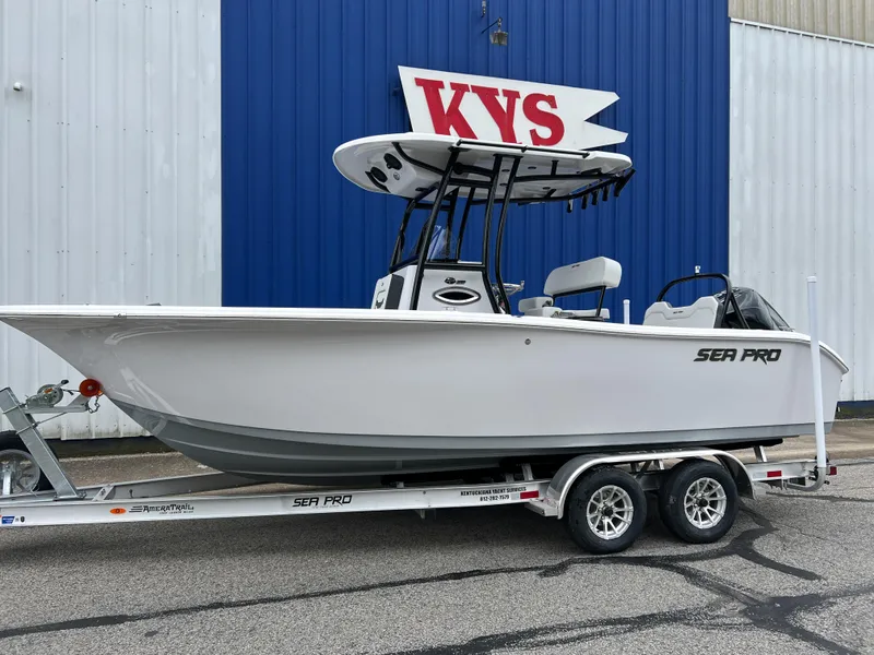 The Image of 2025 Sea Pro 225 Sandbar boat on trailer, parked outside a blue and white building. - 0