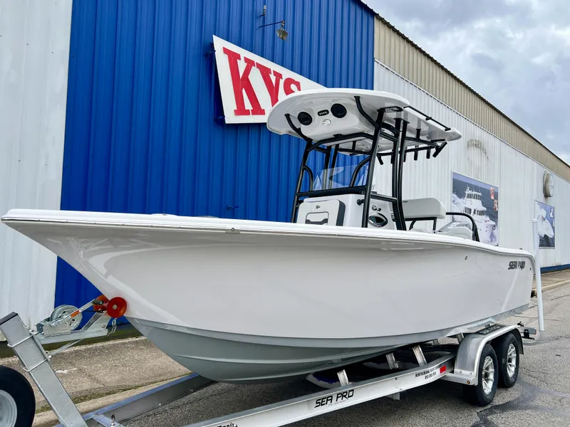 Slide: The Image of 2025 Sea Pro 225 Sandbar boat on trailer, parked outside a blue building. - 1