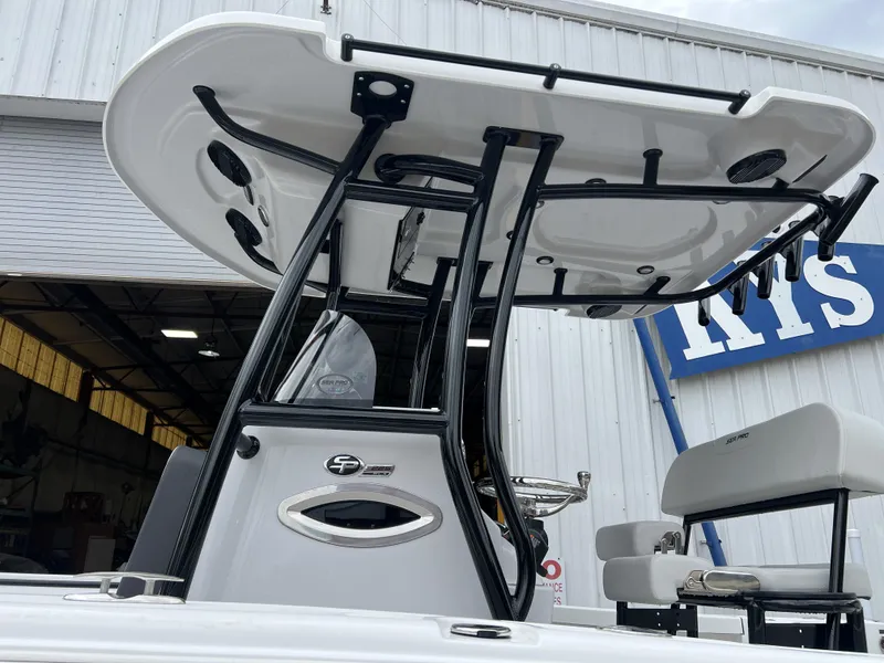 Slide: The Image of 2025 Sea Pro 225 Sandbar boat with T-top, docked near a warehouse. - 3