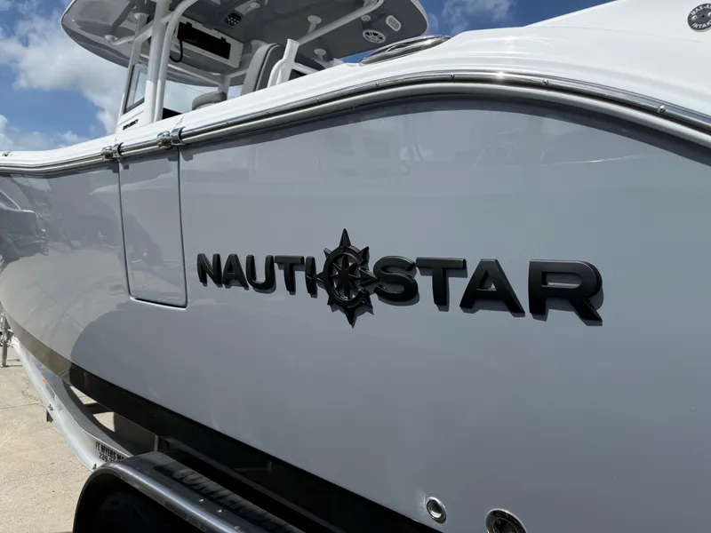 Slide: The Image of 2025 NauticStar 292 Legacy boat side view with logo under blue sky. - 27