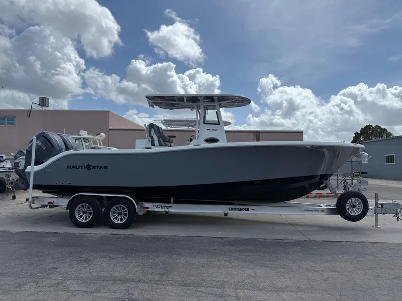 Slide: The Image of 2025 NauticStar 292 Legacy boat on trailer, parked outdoors under cloudy sky. - 29