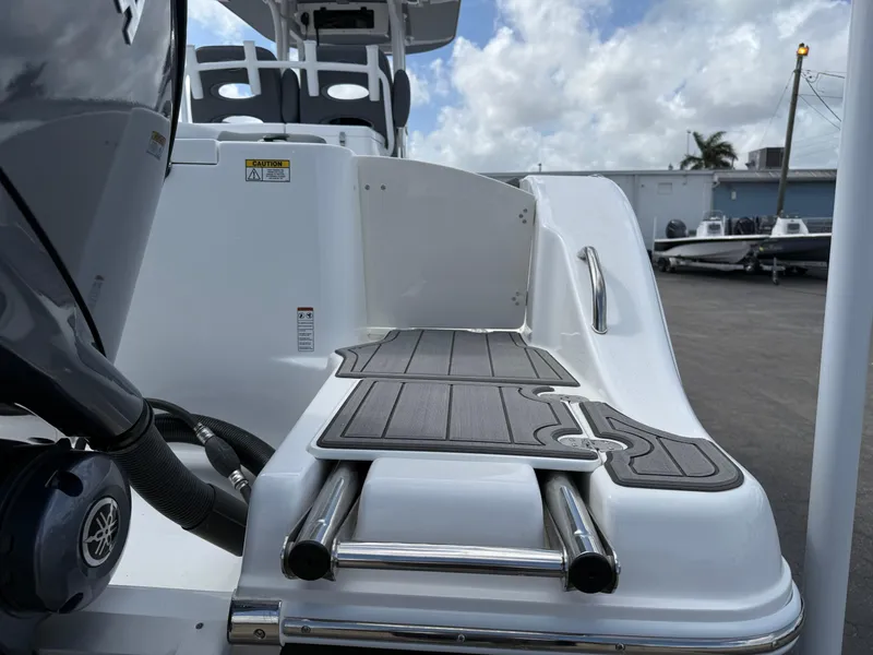 Slide: The Image of 2025 NauticStar 292 Legacy boat with swim platform and ladder, docked under cloudy sky. - 5
