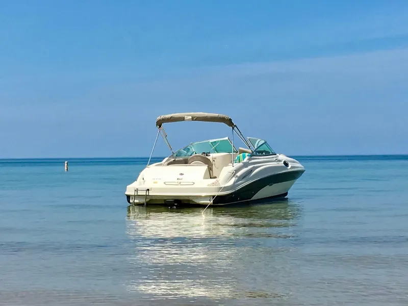 Slide: The Image of 2002 Sea Ray 270 Sundeck boat anchored on calm, clear water under a blue sky. - 16