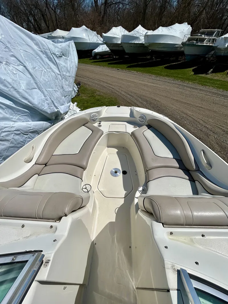 Slide: The Image of 2002 Sea Ray 270 Sundeck boat interior with beige seating, parked among covered boats. - 4