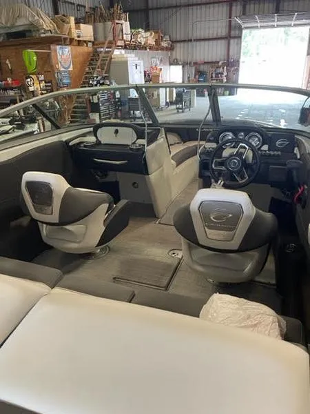 Slide: The Image of 2023 Crownline 200 SS boat interior with modern dashboard and seating in a warehouse setting. - 5