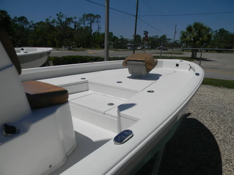 Slide: The Image of 2023 Avid 21 Mag boat, white deck, brown seating, parked outdoors. - 11