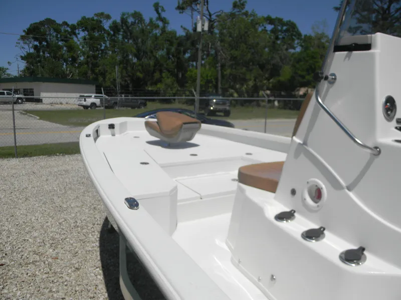 Slide: The Image of 2023 Avid 21 Mag boat with white deck and tan seating, parked outdoors. - 17
