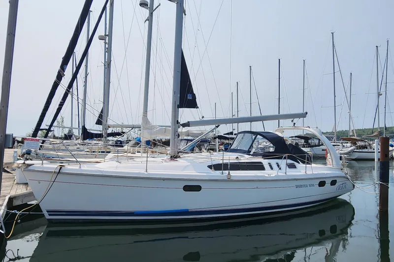 The Image of 1999 Hunter 380 sailboat docked at marina, calm water, clear sky. - 0