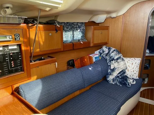 Slide: The Image of Cozy interior of a 1999 Hunter 380 sailboat with blue seating and wooden cabinetry. - 13