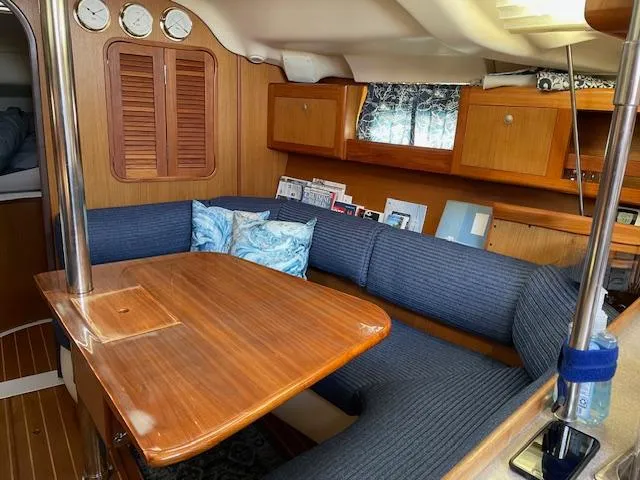 Slide: The Image of Cozy interior of a 1999 Hunter 380 sailboat with wooden table and blue seating. - 14