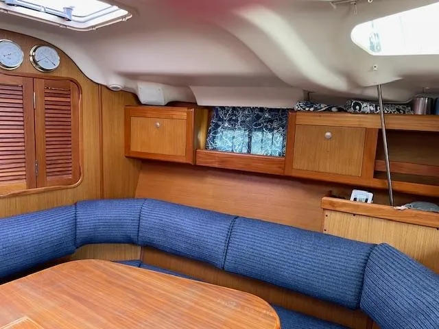 Slide: The Image of Interior of a 1999 Hunter 380 sailboat with blue seating and wooden cabinets. - 15