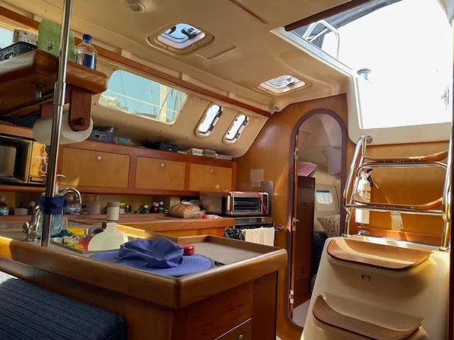 Slide: The Image of Interior of a 1999 Hunter 380 sailboat, featuring a cozy kitchen and dining area. - 16
