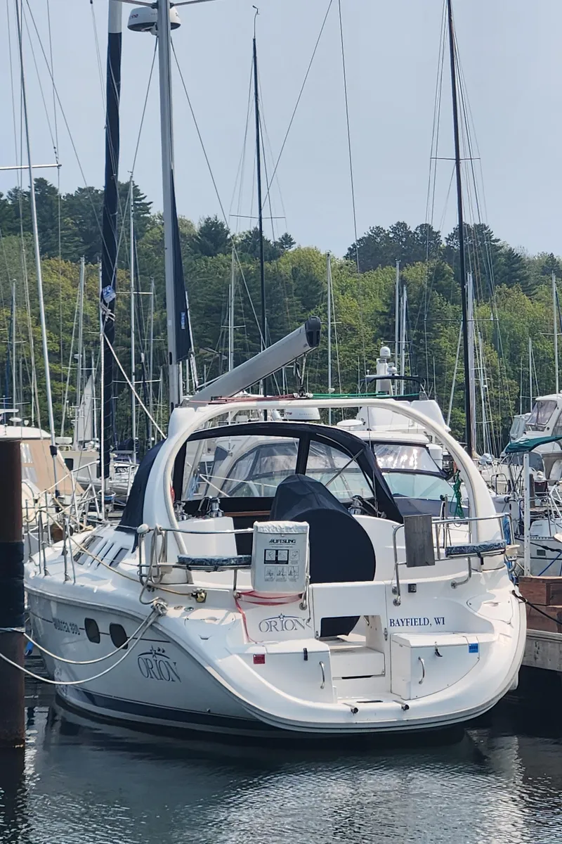Slide: The Image of 1999 Hunter 380 sailboat docked in a marina, surrounded by other boats and trees. - 2