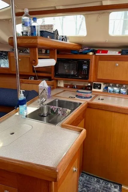 Slide: The Image of 1999 Hunter 380 yacht interior kitchen with sink, microwave, and wooden cabinetry. - 22