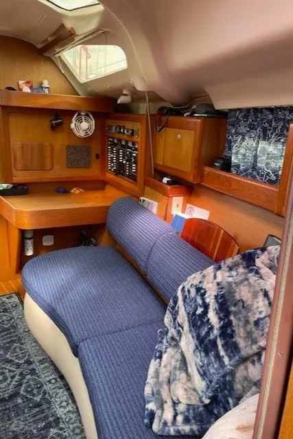 Slide: The Image of Cozy interior of a 1999 Hunter 380 sailboat with blue seating and wooden accents. - 25