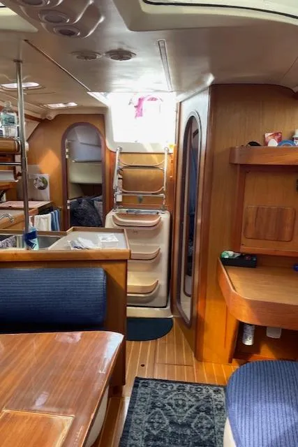 Slide: The Image of Interior of a 1999 Hunter 380 sailboat with wooden furnishings and blue seating. - 26