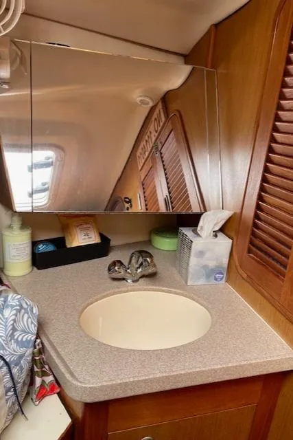Slide: The Image of 1999 Hunter 380 yacht bathroom with sink, mirror, and wooden cabinetry. - 27