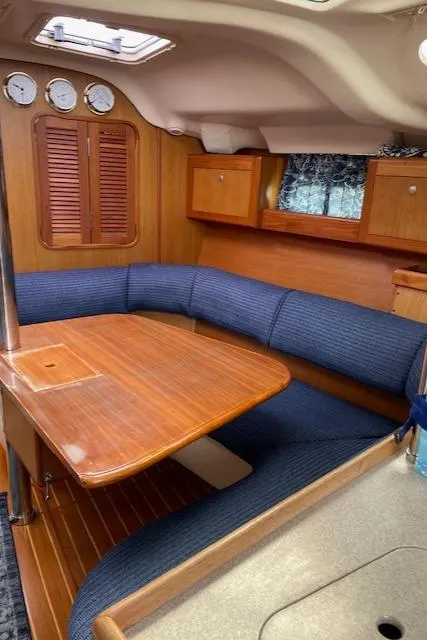 Slide: The Image of Interior of a 1999 Hunter 380 sailboat with wooden table and blue seating. - 28