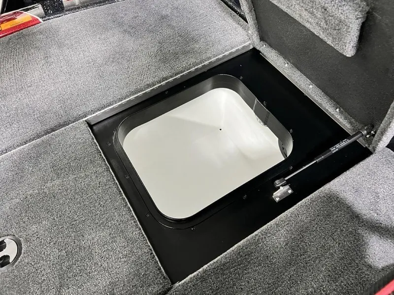 Slide: The Image of 2025 Skeeter ZXR20 boat storage compartment with open hatch, featuring gray carpeted interior. - 25