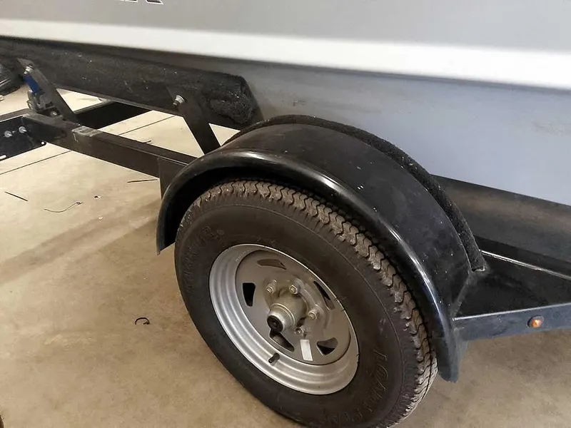 Slide: The Image of 2024 SeaArk 1652 Crappie boat trailer with black fender and tire in garage. - 14
