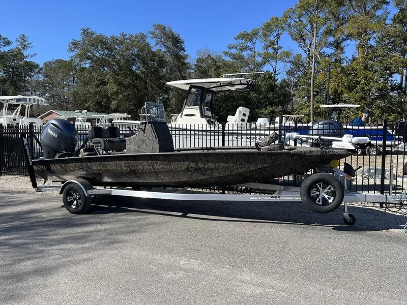 Slide: The Image of 2025 Xpress H210B boat on trailer, parked outdoors near other boats. - 0