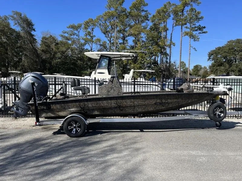 Slide: The Image of 2025 Xpress H210B boat on trailer, parked outdoors with trees in background. - 1