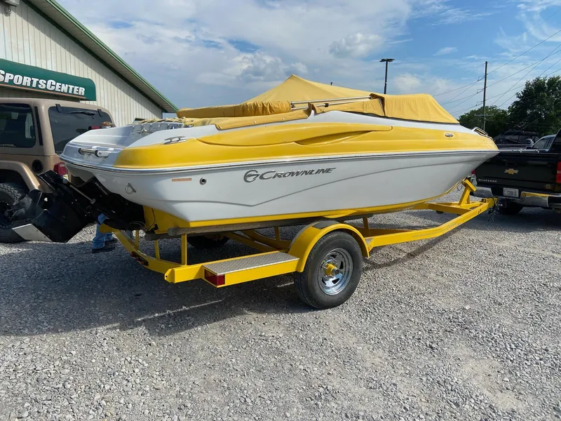 The Image of 2013 Crownline 21 SS boat with yellow cover on trailer, parked outdoors. - 1