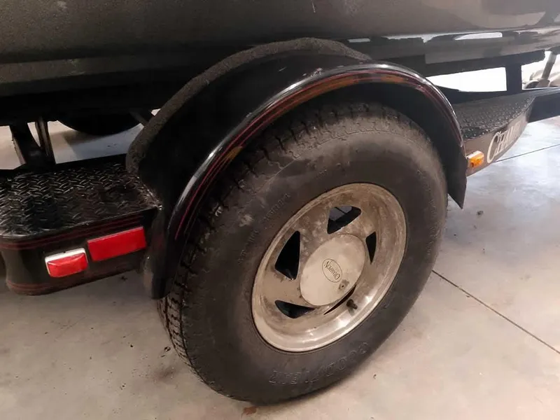 Slide: The Image of Trailer wheel of a 1999 Champion 171 boat, featuring a sturdy tire and fender. - 12