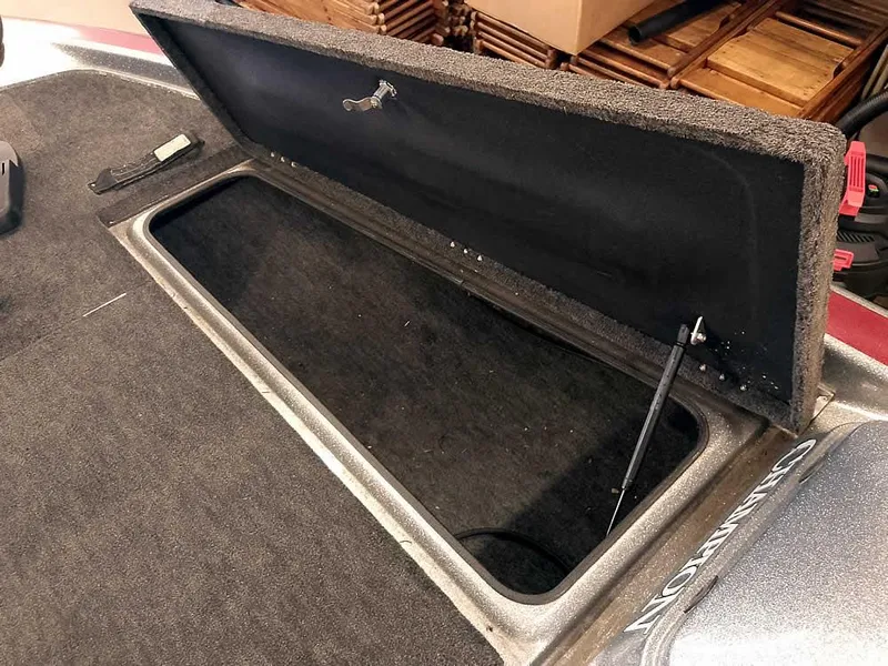 Slide: The Image of Open storage compartment in a 1999 Champion 171 boat, featuring carpeted interior. - 16