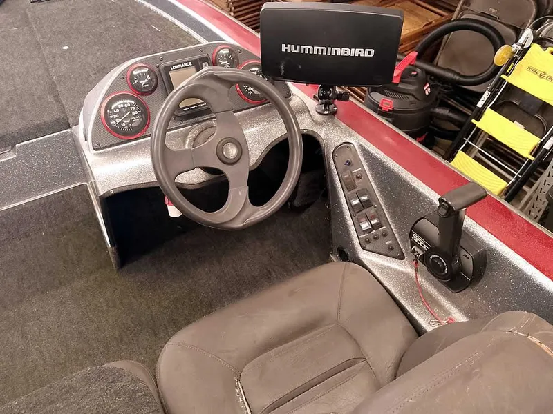 Slide: The Image of 1999 Champion 171 boat cockpit with steering wheel, Humminbird display, and control panel. - 24