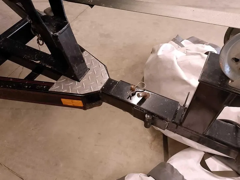 Slide: The Image of Trailer hitch of a 1999 Champion 171, featuring a sturdy metal frame and safety chains. - 36